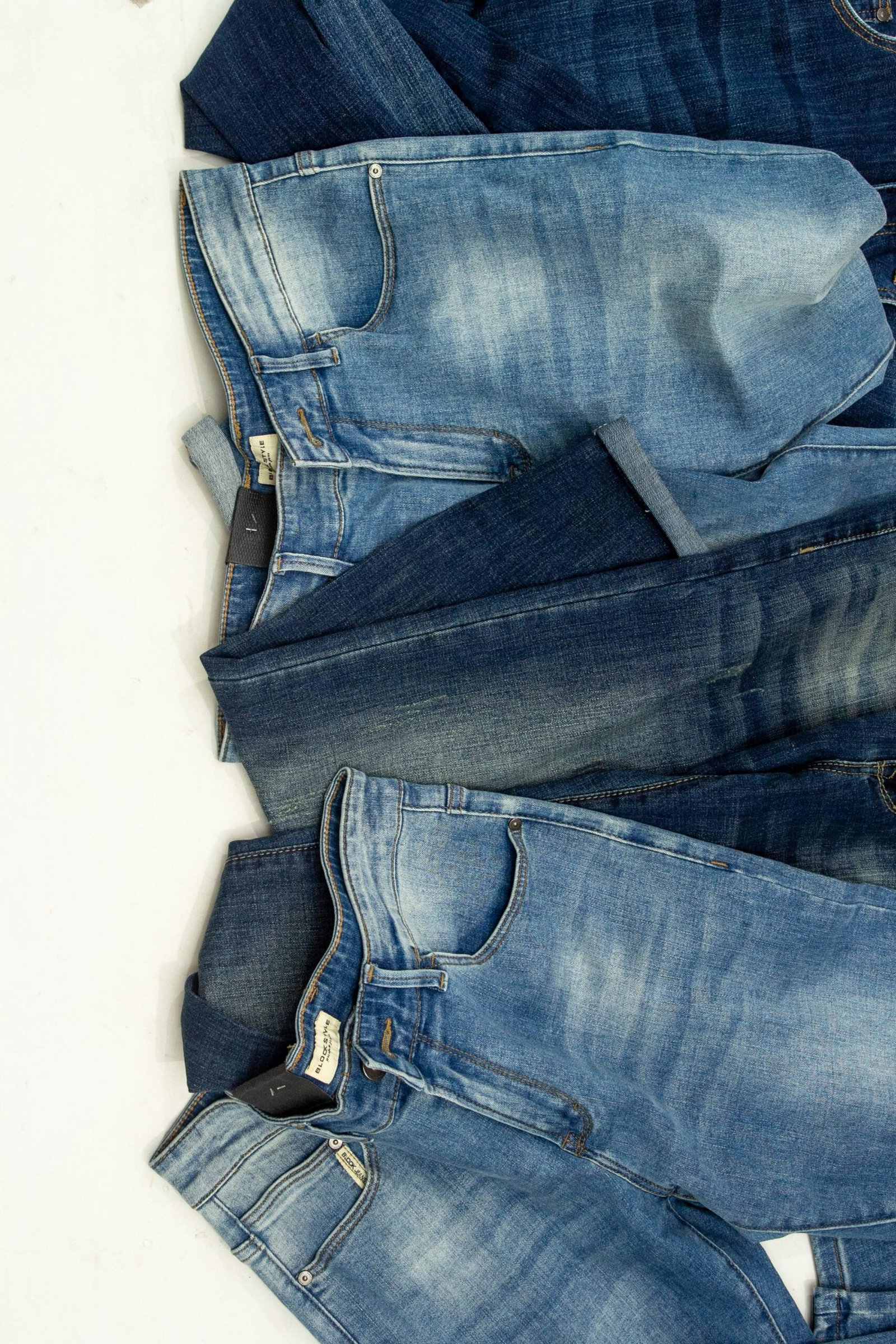 Assorted blue denim jeans laid flat, showing different washes and fits